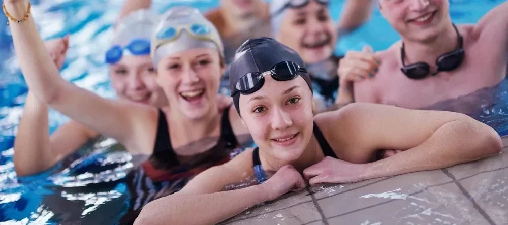 happy teen group at swimming pool class learning to swim and have fun